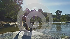 Backside View Girl with Ponytail Holds Pose on River Stone