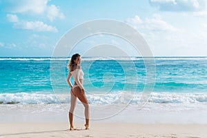 Backside view of girl with sexy booty in beige colour bikini resting on deserted beach