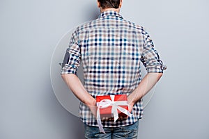Backside view of man prepared red gift box with white ribbon on