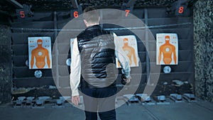 Backside view of a man walking towards target lists in a shooting gallery