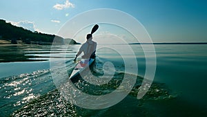 Backside view of an oarsman paddling along the water