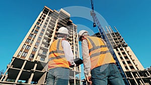 Backside view of two engineers at high-rise buildings in progress