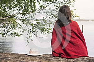 Backside of woman sitting on tree in front of a lake