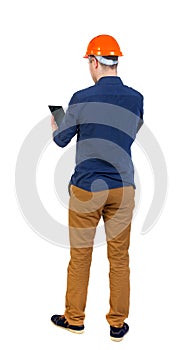 Backview of business man in construction helmet stands and enjoy