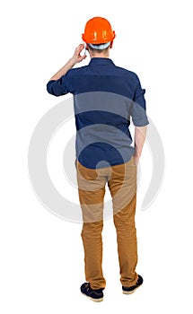 Backview of business man in construction helmet stands and enjoy