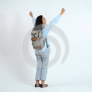 backview full leght shoot of happy asian Indonesian woman wearing casual attire and backpack on isolated background photo