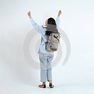 backview full leght shoot of happy asian Indonesian woman wearing casual attire and backpack on isolated background photo