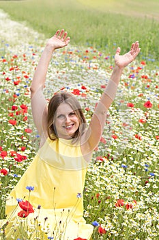 Backview of a girl walking among red poppy flowers at the field. Young woman feels happy and enjoys freedom