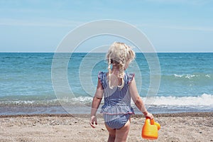 Backview of little girl playing at the beach photo