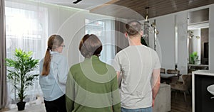 Backview of woman professional real estate agent make a apartment tour shows modern design for a young family couple
