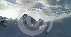 Backward aerial from snowy mounts at Valparola pass.Sunny sunset or sunrise, cloudy sky with backlit sun.Winter