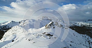 Backward aerial from snowy mounts at Valparola pass.Sunny sunset or sunrise, cloudy sky.Winter Dolomites Italian Alps