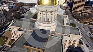 Backwards aerial shot of the Georgia Capitol Museum surrounded by skyscrapers and office buildings with cars driving