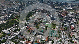 Backwards fly above town development. Tilt up reveal downtown and sea coast with harbour. Cape Town, South Africa