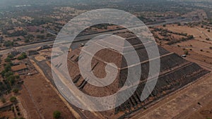 Backwards reveal of ancient huge pyramid. Tilt up to view dry landscape. Ancient site with architecturally significant