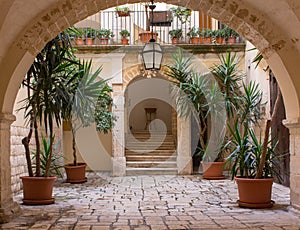 Backyard with arch, plants in pots, stairs and lantern. Patio decoration. Ancient courtyard background. Medieval architecture.