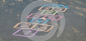 Backyard classics on an asphalt floor with chalk drawn numbers and squares. Selective focus