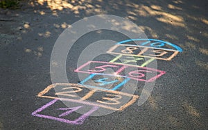 Backyard classics on an asphalt floor with chalk drawn numbers and squares. Selective focus