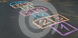 Backyard classics on an asphalt floor with chalk drawn numbers and squares. Selective focus