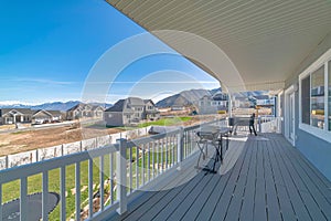 Backyard deck of a house with barbecue grills and a lawn with tarpauline and vinyl fence