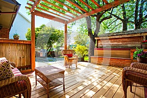 Backyard deck with wicker furniture and pergola.