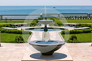 The backyard of a landscaped mansion with a stone fountain.