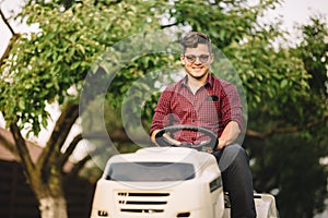 Backyard lawncare man portrait - Smiling worker using ride on grass mower