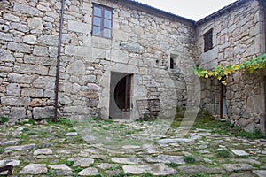 Backyard of old house in village. Stone medieval building with open entrance and windows.