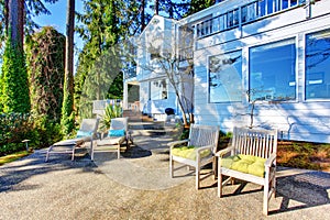 Backyard patio area with chairs, concrete walkway and landscaping desing.