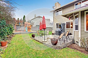 Backyard patio area with table set and closed red umbrella