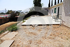 Backyard with patio slab and weeds and stucco house