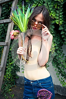 Backyard summer fashion young woman with sunglasses and bouquet