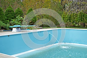 Backyard swimming pool with diving board emptied out shutting down for winter