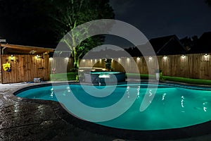 A backyard swimming pool and jacuzzi hot tob at night