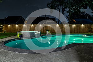 A backyard swimming pool and jacuzzi hot tob at night