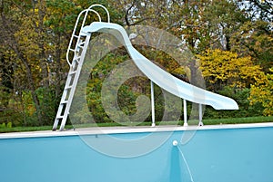 Backyard swimming pool with pool slide emptied out shutting down for winter