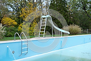 Backyard swimming pool with pool slide and ladder emptied out shutting down for winter