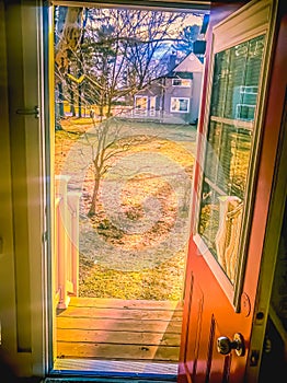 Backyard with trees and a house in background, seen through an opened door.