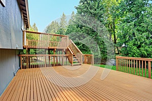 Backyard view of grey rambler house with upper and lower decks photo