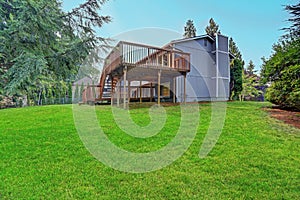 Backyard view of grey rambler house with upper and lower decks