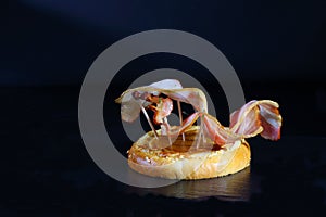 Burger bacon on a bun on a black background