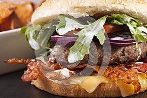 Bacon cheese bbq burger on wooden table with fries