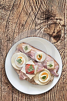 Bacon And Egg Sandwich With An Extra Belly Bacon Rasher On White Porcelain Plate Set On Old Rustic Rough Pinewood Picnic Table