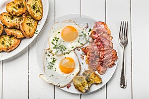 Bacon and eggs for breakfast with chives and bread
