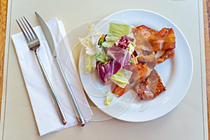 Bacon ham slice and salad on white plate in restaurant
