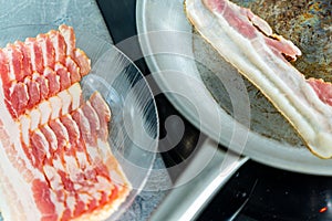 Bacon on a plate, prepared for pan-frying. One piece of bacon in a pan. Delicious junk food.