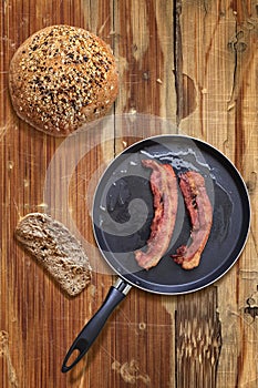 Fried Pork Ham Rashers In Teflon Frying Pan With Integral Brown Bread Loaf And Slice Set On Old Cracked Picnic Table photo