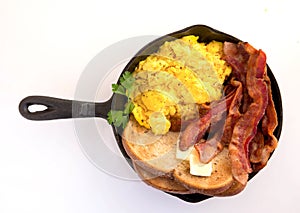 Bacon,scrambled eggs and toast in cast iron skillet white backgorund