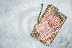 Bacon slices. Pig meat. Pork belly with rosemary on a light background, Keto diet food ingredients. Long banner format. top view