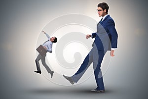 The bad angry boss kicking employee in business concept